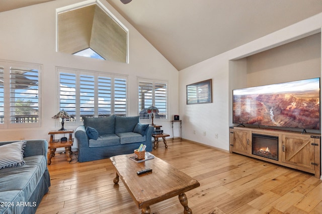 living room featuring light wood-type flooring, high vaulted ceiling, and plenty of natural light