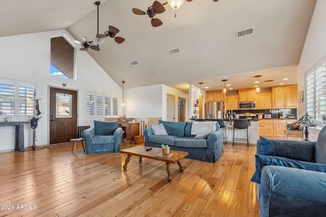 living room featuring light hardwood / wood-style floors, high vaulted ceiling, and ceiling fan