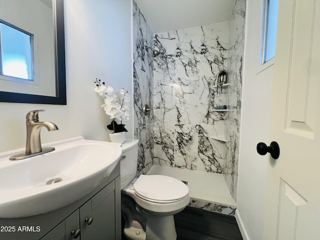 bathroom featuring toilet, vanity, and tiled shower