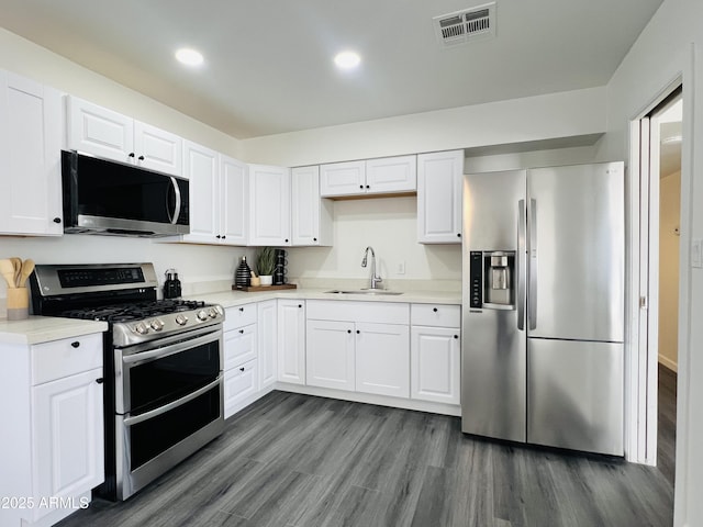 kitchen with dark hardwood / wood-style flooring, sink, white cabinetry, and stainless steel appliances