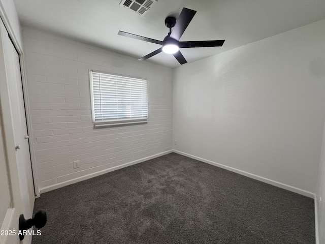 carpeted spare room with ceiling fan and brick wall