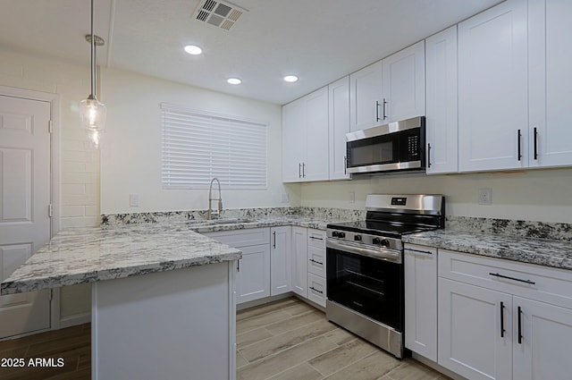 kitchen featuring kitchen peninsula, appliances with stainless steel finishes, hanging light fixtures, white cabinets, and sink