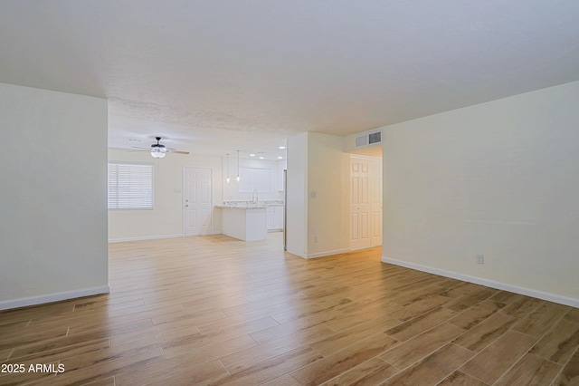 unfurnished room featuring ceiling fan, light hardwood / wood-style flooring, and sink