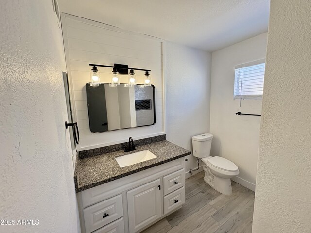6419 W Monte Cristo Ave, Glendale, AZ 85306 - bathroom featuring wood finished floors, vanity, toilet, a textured wall, and baseboards