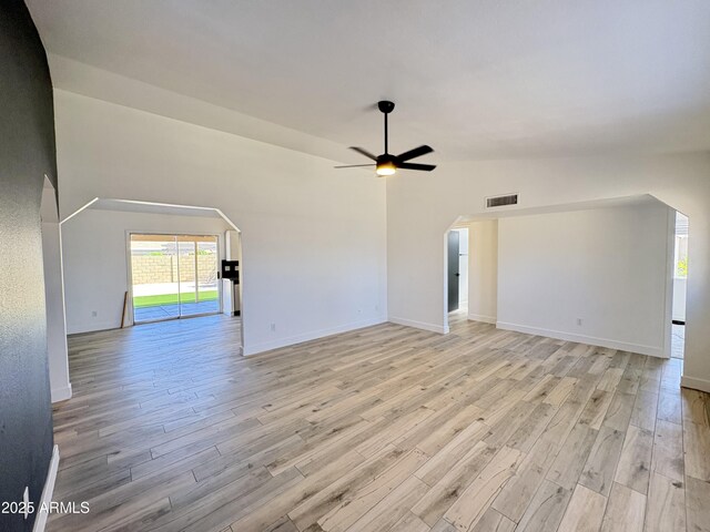6419 W Monte Cristo Ave, Glendale, AZ 85306 - unfurnished living room with light wood-style floors, arched walkways, ceiling fan, and baseboards