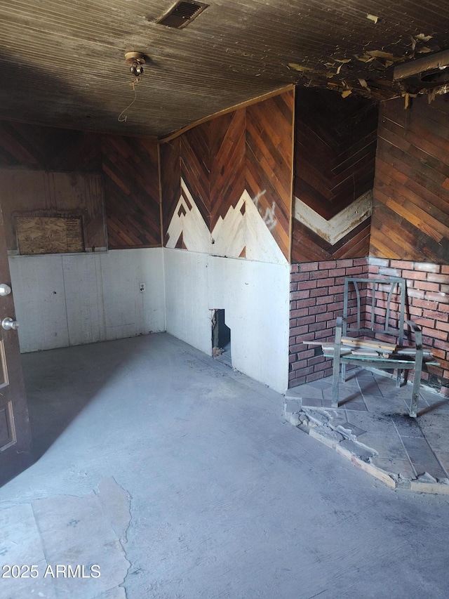 interior space featuring concrete floors, wooden ceiling, visible vents, and wood walls