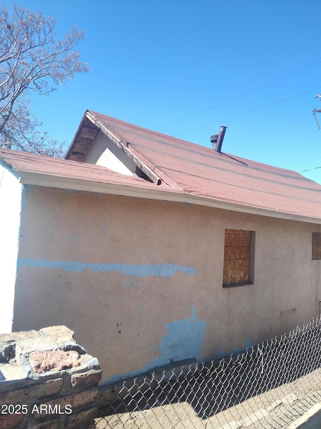 view of side of property featuring stucco siding and fence