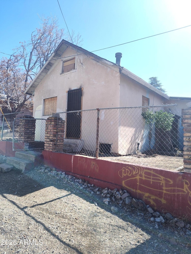 view of property exterior with stucco siding and fence