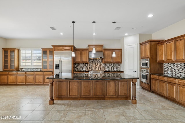 kitchen with stainless steel appliances, tasteful backsplash, ventilation hood, pendant lighting, and a kitchen island with sink