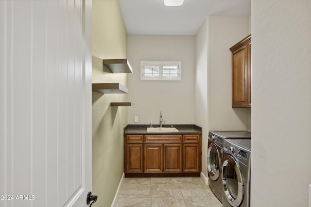 clothes washing area with cabinets, light tile patterned floors, washer and dryer, and sink