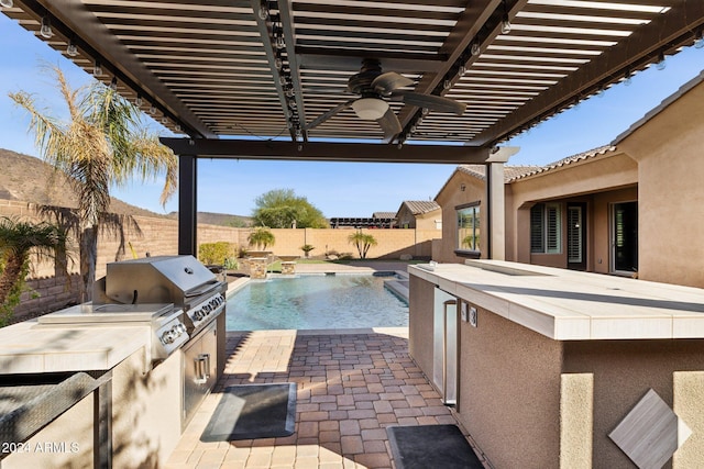 view of patio with a bar, a fenced in pool, area for grilling, and ceiling fan