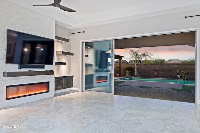 unfurnished living room with ceiling fan and an outdoor stone fireplace