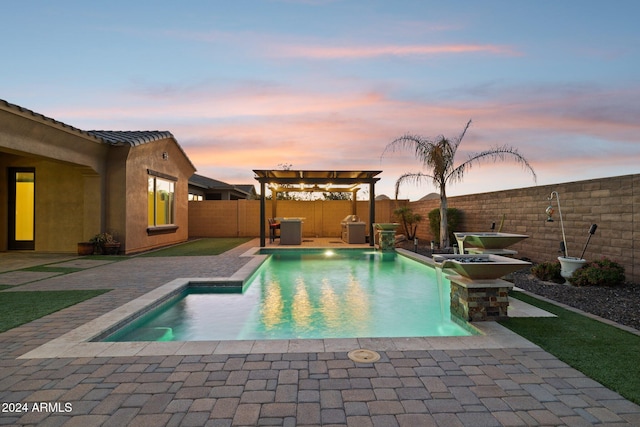 pool at dusk with pool water feature and a patio