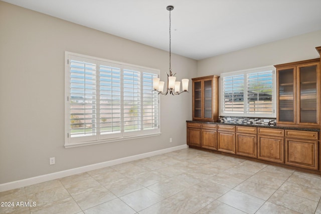 12860 W Calle De Sol, Peoria, AZ 85383 - unfurnished dining area featuring plenty of natural light, a chandelier, baseboards, and light tile patterned floors