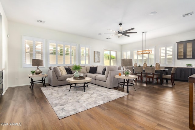 living room with ceiling fan with notable chandelier and dark wood-type flooring