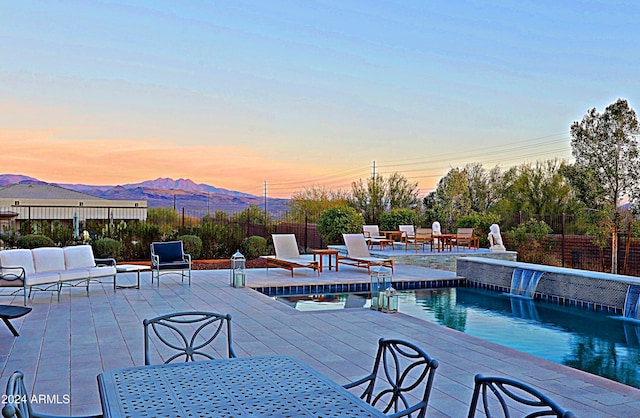 pool at dusk with pool water feature and a deck with mountain view