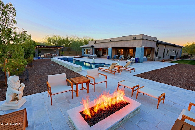 pool at dusk with a patio area, area for grilling, and an outdoor fire pit