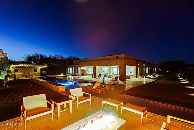 pool at twilight with an in ground hot tub, a patio, and a fire pit