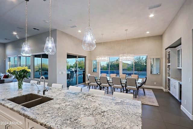 kitchen featuring decorative light fixtures, white cabinetry, light stone counters, and sink