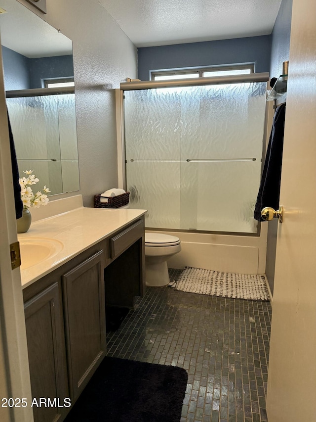 full bathroom with toilet, brick floor, vanity, and bath / shower combo with glass door
