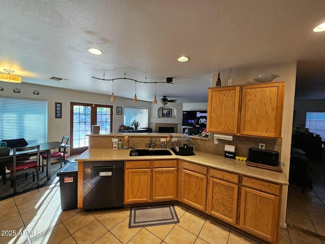 kitchen featuring visible vents, dishwasher, a peninsula, light tile patterned flooring, and a sink