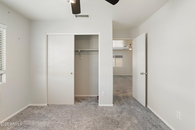 unfurnished bedroom featuring carpet, visible vents, a closet, and a ceiling fan