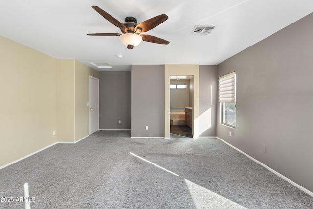 unfurnished bedroom featuring baseboards, carpet flooring, ensuite bathroom, visible vents, and ceiling fan