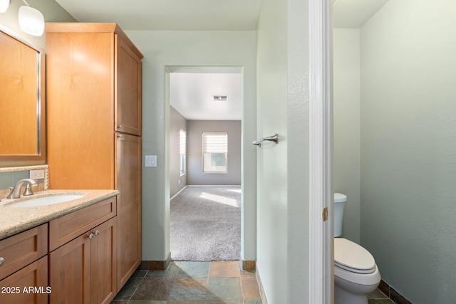 bathroom featuring toilet, vanity, baseboards, and visible vents