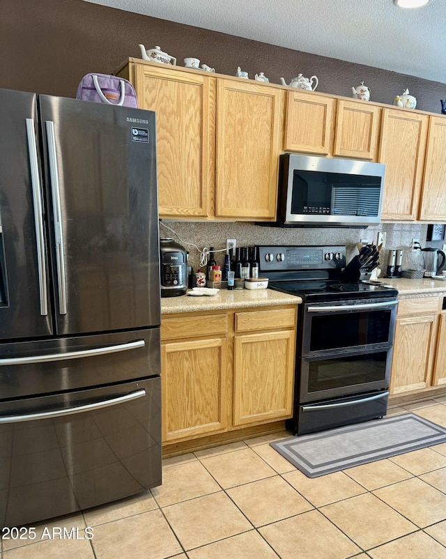 kitchen featuring stainless steel appliances, light tile patterned floors, light brown cabinets, and light countertops