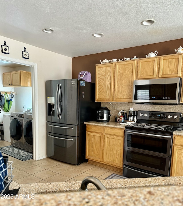 kitchen featuring fridge with ice dispenser, light countertops, stainless steel microwave, range with two ovens, and washing machine and dryer