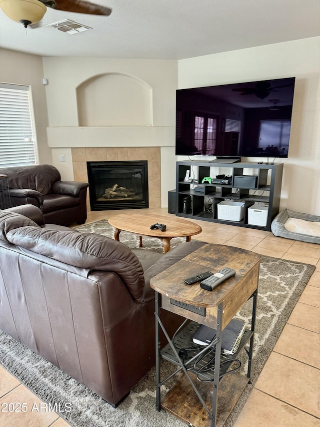 living room with ceiling fan, a fireplace, tile patterned flooring, and visible vents