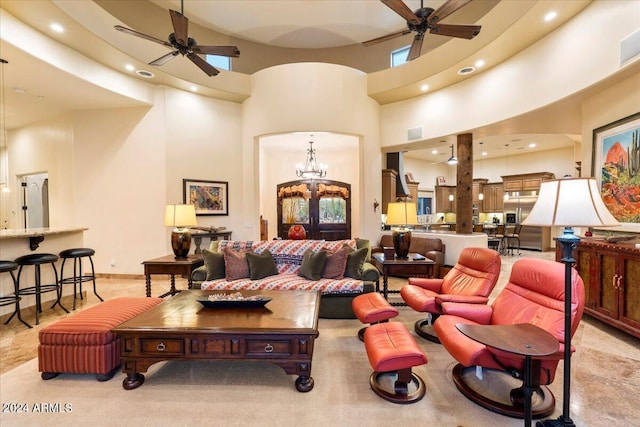 carpeted living room with ceiling fan with notable chandelier and a high ceiling