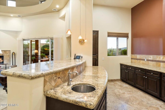 kitchen featuring sink, a kitchen island, light stone counters, and decorative light fixtures