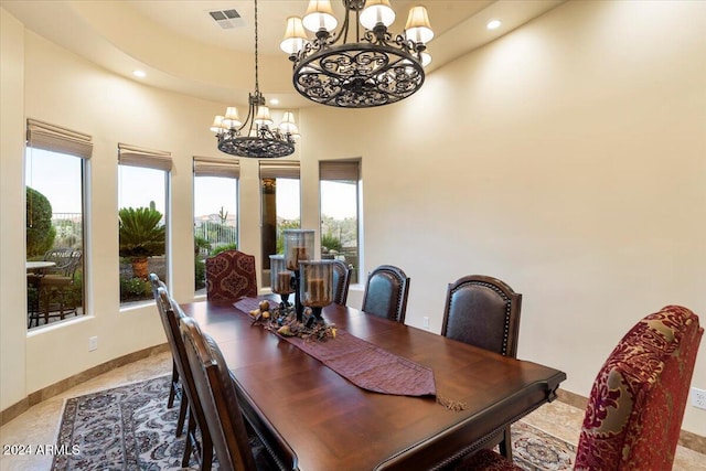 dining area featuring a towering ceiling and an inviting chandelier