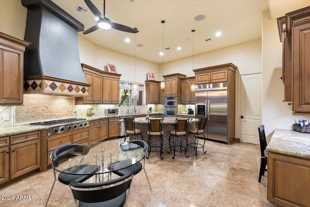 kitchen featuring custom range hood, stainless steel appliances, ceiling fan, and light stone counters