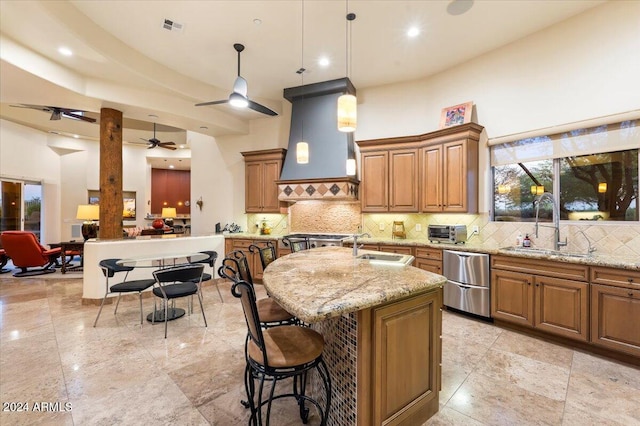 kitchen featuring light stone counters, hanging light fixtures, sink, custom exhaust hood, and a kitchen island with sink