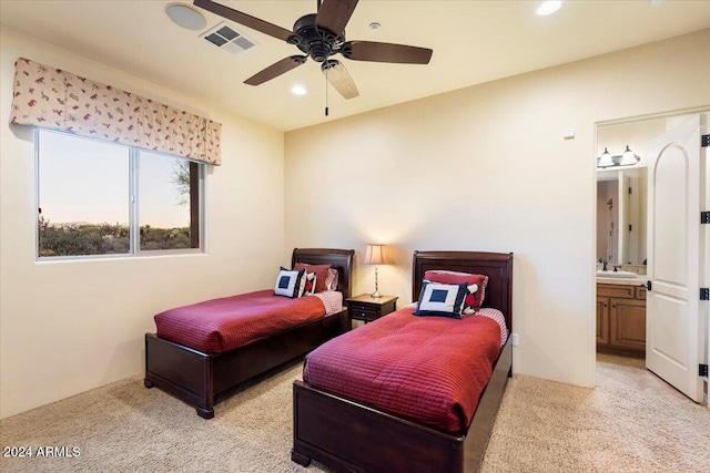 bedroom with ensuite bathroom, ceiling fan, sink, and light colored carpet