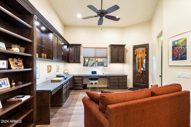 kitchen with dark brown cabinetry, light hardwood / wood-style flooring, built in desk, and ceiling fan