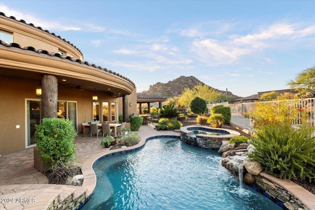 view of swimming pool with a mountain view, ceiling fan, a patio, and an in ground hot tub