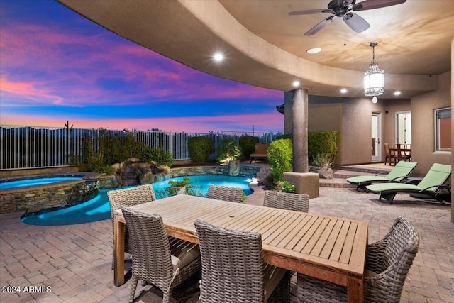 patio terrace at dusk featuring a swimming pool with hot tub and ceiling fan