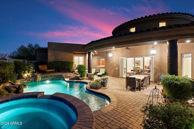 pool at dusk featuring a patio and an in ground hot tub