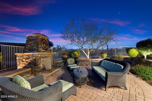 patio terrace at dusk featuring an outdoor stone fireplace