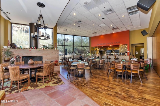 dining room featuring a chandelier, hardwood / wood-style flooring, a healthy amount of sunlight, and a towering ceiling