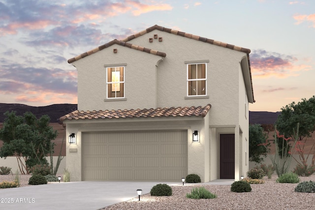 mediterranean / spanish house featuring a mountain view, stucco siding, an attached garage, and concrete driveway