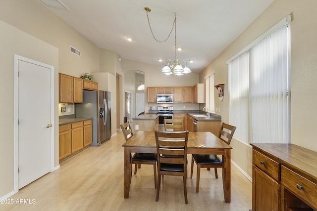 dining area with light wood-type flooring, a notable chandelier, and sink