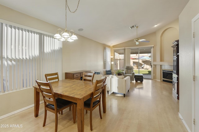 dining room with ceiling fan with notable chandelier, lofted ceiling, and light hardwood / wood-style flooring