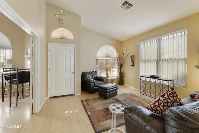 living room with a high ceiling, light hardwood / wood-style floors, and a notable chandelier