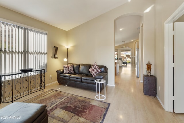 living room with light wood-type flooring, ceiling fan, and vaulted ceiling