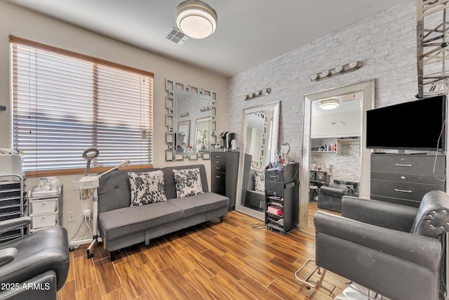living area featuring brick wall, wood finished floors, and visible vents