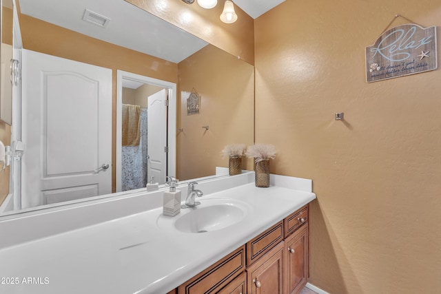 bathroom with a textured wall, vanity, and visible vents